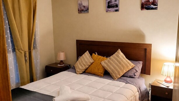 A hotel room with a bed, a nightstand, a lamp, and a ceiling fan. - Cozy and spacious home with parking (Los Angeles)