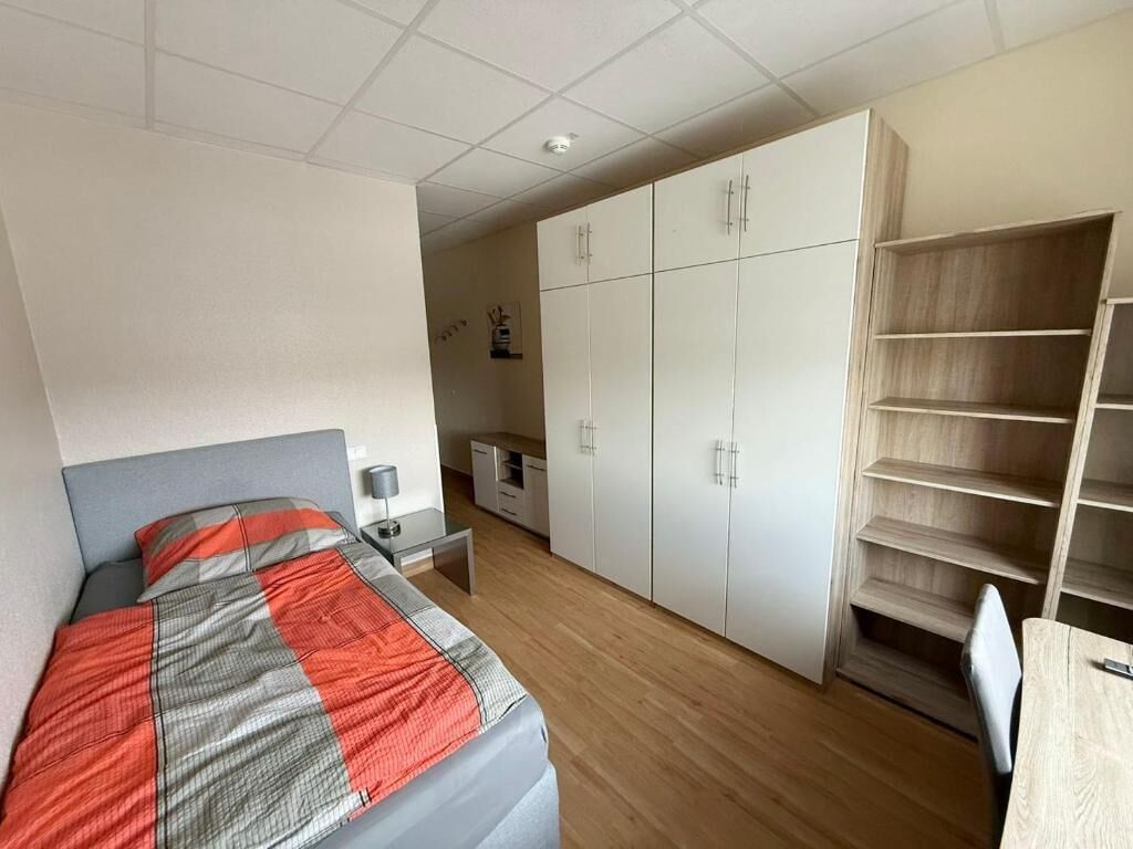 Quarto com cama, guarda-roupa, escrivaninha e cadeira.