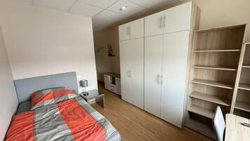 Quarto com cama, guarda-roupa, escrivaninha e cadeira.