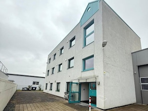 A multi-story building with a flat roof, a ground entrance with a door, and a visible number '9' on the door.