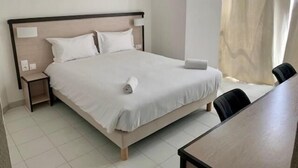 Een hotelkamer met een bed, nachtkastjes, een stoel en een raam met gordijnen.