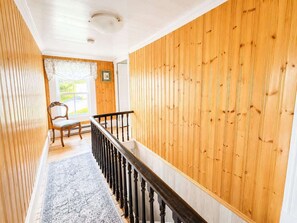 A wooden interior with a staircase, a chair, and a window. - Hawkins House & Henry's Hideaway (Twillingate)