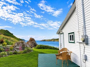 A white house with a green deck, a window with a green frame, and a view of the sea. - Hawkins House & Henry's Hideaway (Twillingate)