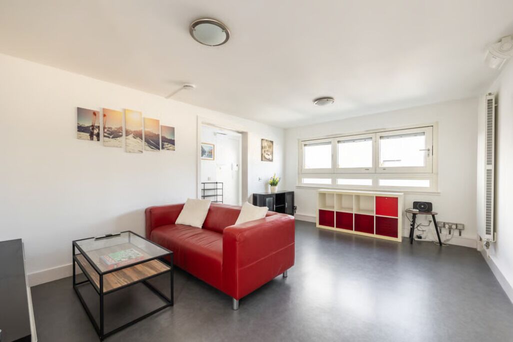 Een moderne woonkamer met een rode bank, een glazen salontafel en een rode en witte kast.