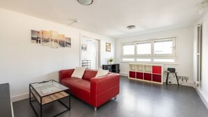 Ett modernt vardagsrum med en röd soffa, ett soffbord i glas och ett rött och vitt skåp.