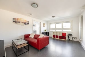Een moderne woonkamer met een rode bank, een glazen salontafel en een rode en witte kast.