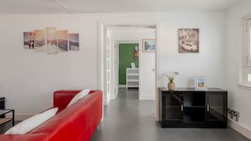 Een moderne woonkamer met een rode bank, een zwarte kast en kunstwerken aan de muren.