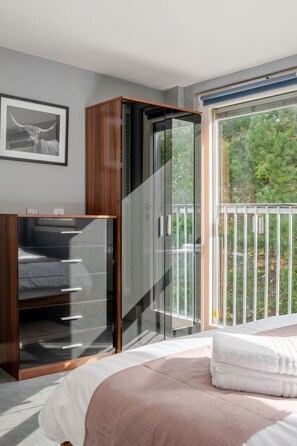 A bedroom with a bed, a wardrobe, and a sliding glass door leading to a balcony.