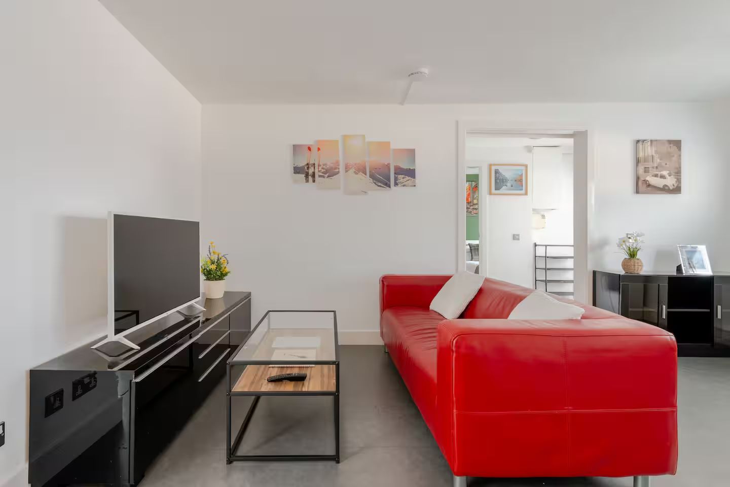 Un salon moderne avec un canapé rouge, un téléviseur à écran plat et une table basse.