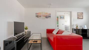 Un salon moderne avec un canapé rouge, un téléviseur à écran plat et une table basse.