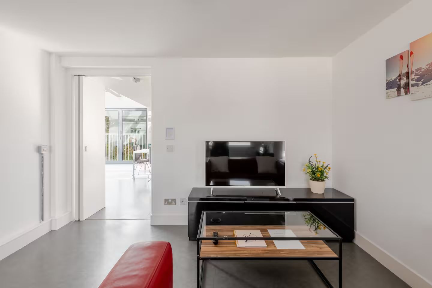 A modern living room with a flat-screen TV, a wooden coffee table, and a red bench.