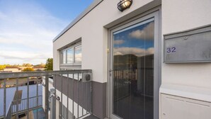 En modern byggnad med en stor skjutdörr av glas, en grind av metall och en brevlåda med nummer 32.