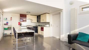 A modern kitchen with a dining area, a sofa, and a small window.