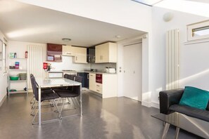 A modern kitchen with a dining area, a sofa, and a small window.