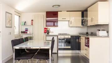 Une cuisine moderne équipée d’une table à manger, de chaises, d’une cuisinière, d’un four, d’un four à micro-ondes et de placards.