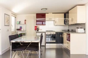 A modern kitchen with a dining table, chairs, a stove, oven, microwave, and cabinets. - Spacious 2-Bed Apartment, Arthur's Seat Views (Edinburgh)