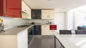 Ett modernt kök med gasspis, ugn och diskmaskin, samt en matplats med bord och stolar.