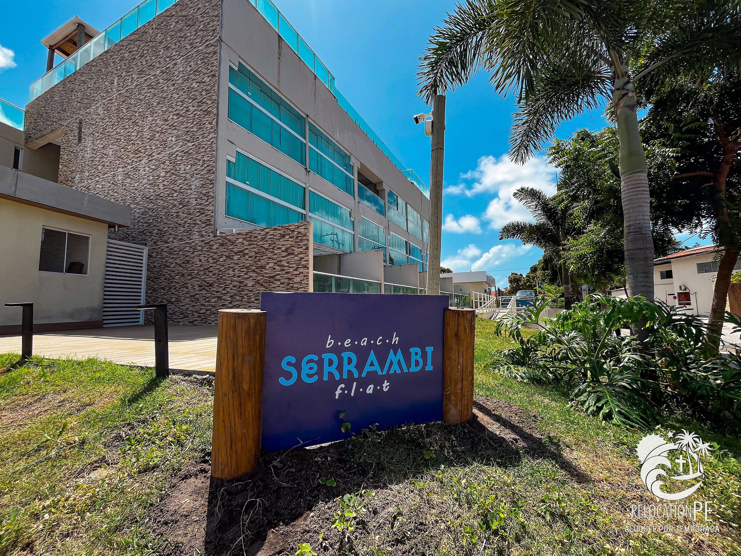 Une enseigne pour un hôtel appelé « SERRA AMBI », avec un bâtiment moderne en arrière-plan.