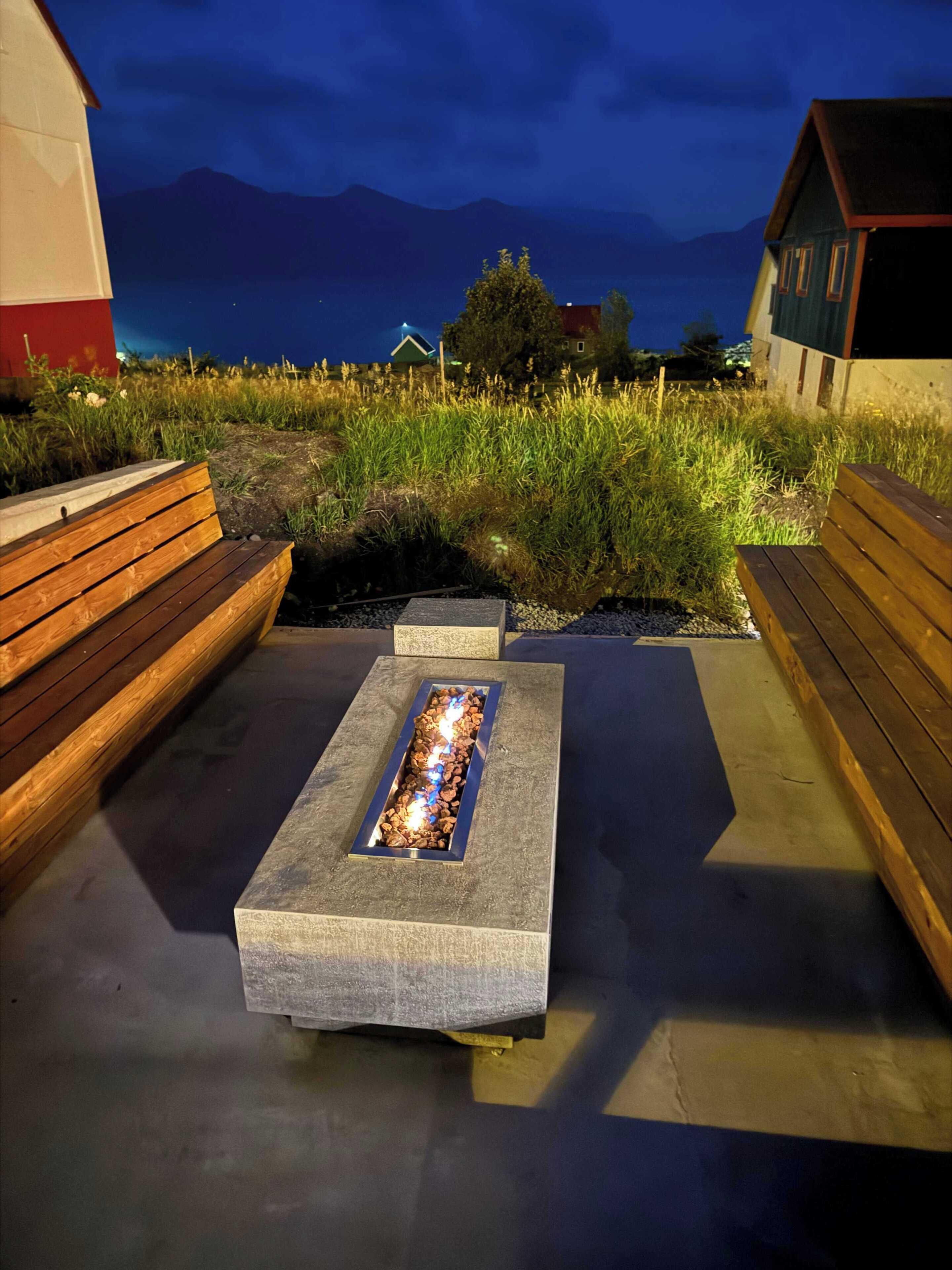 Un espace extérieur aménagé avec des bancs et un foyer.