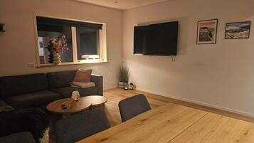 Un salon avec un canapé, une table basse et un téléviseur fixé au mur.