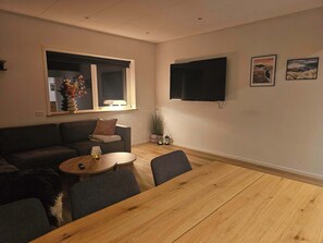 A living room with a sofa, a coffee table, and a TV mounted on the wall.