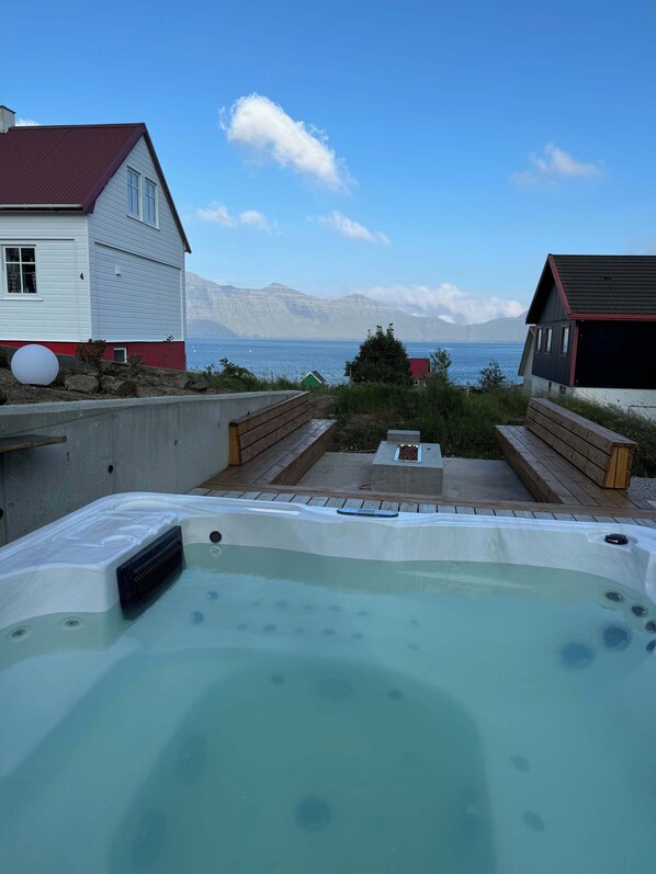 A hot tub with a view of the sea and mountains in the background.