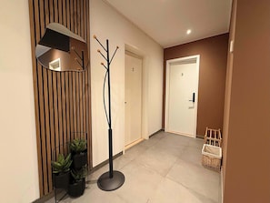 Un couloir avec un lampadaire au design moderne, un porte-manteau et une porte portant le numéro 3.