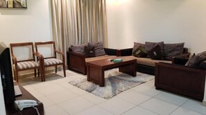 Una sala de estar con un sofá, dos sillones, una mesa de centro y un televisor.