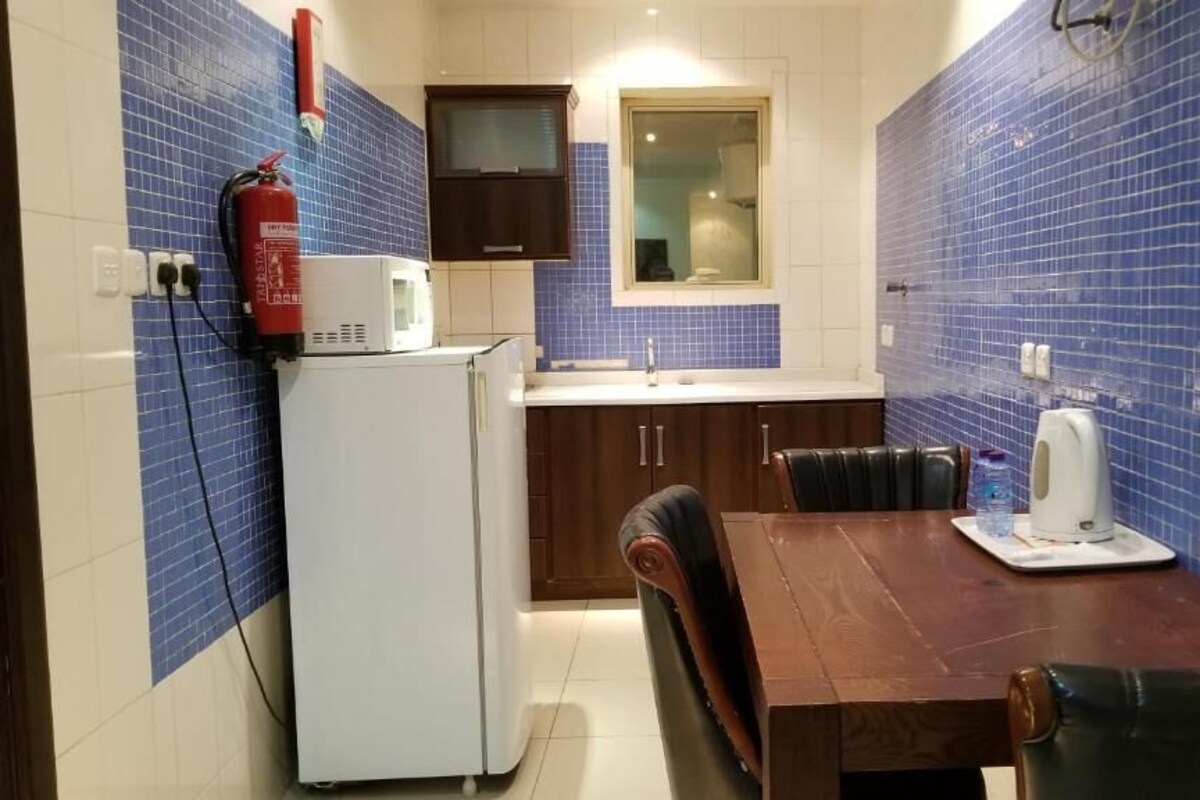 Cocina compacta con microondas, lavamanos y una mesa de comedor con sillas.