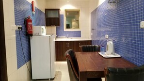 Cocina compacta con microondas, lavamanos y una mesa de comedor con sillas.