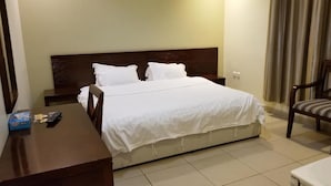 Une chambre d’hôtel avec un lit, une table de chevet, une chaise et un bureau avec une télécommande.