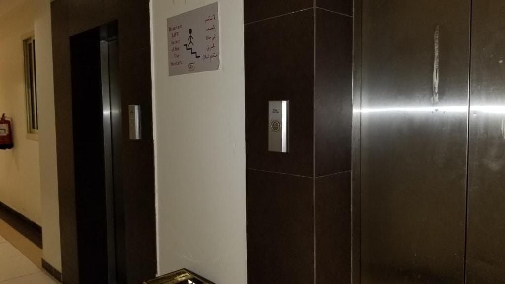 Un pasillo con un ascensor y un extintor en la pared.