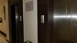 Un pasillo con un ascensor y un extintor en la pared.