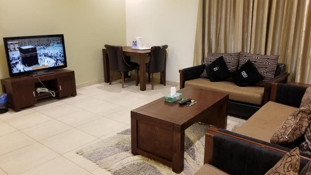 A living room with a television, a coffee table, a sofa, and a dining table.