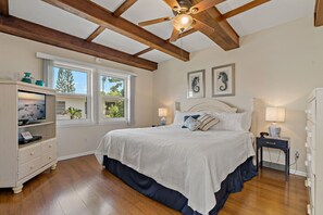 A bedroom with a large bed, wooden beams, a TV, and a dresser. - Beachfront I Private Deck I Pool I Villa 83 (Longboat Key)