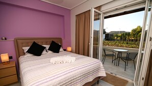 Une chambre à coucher avec un lit, deux lampes de chevet, une fenêtre avec des rideaux et une vue sur un balcon équipé d’une table et de chaises.