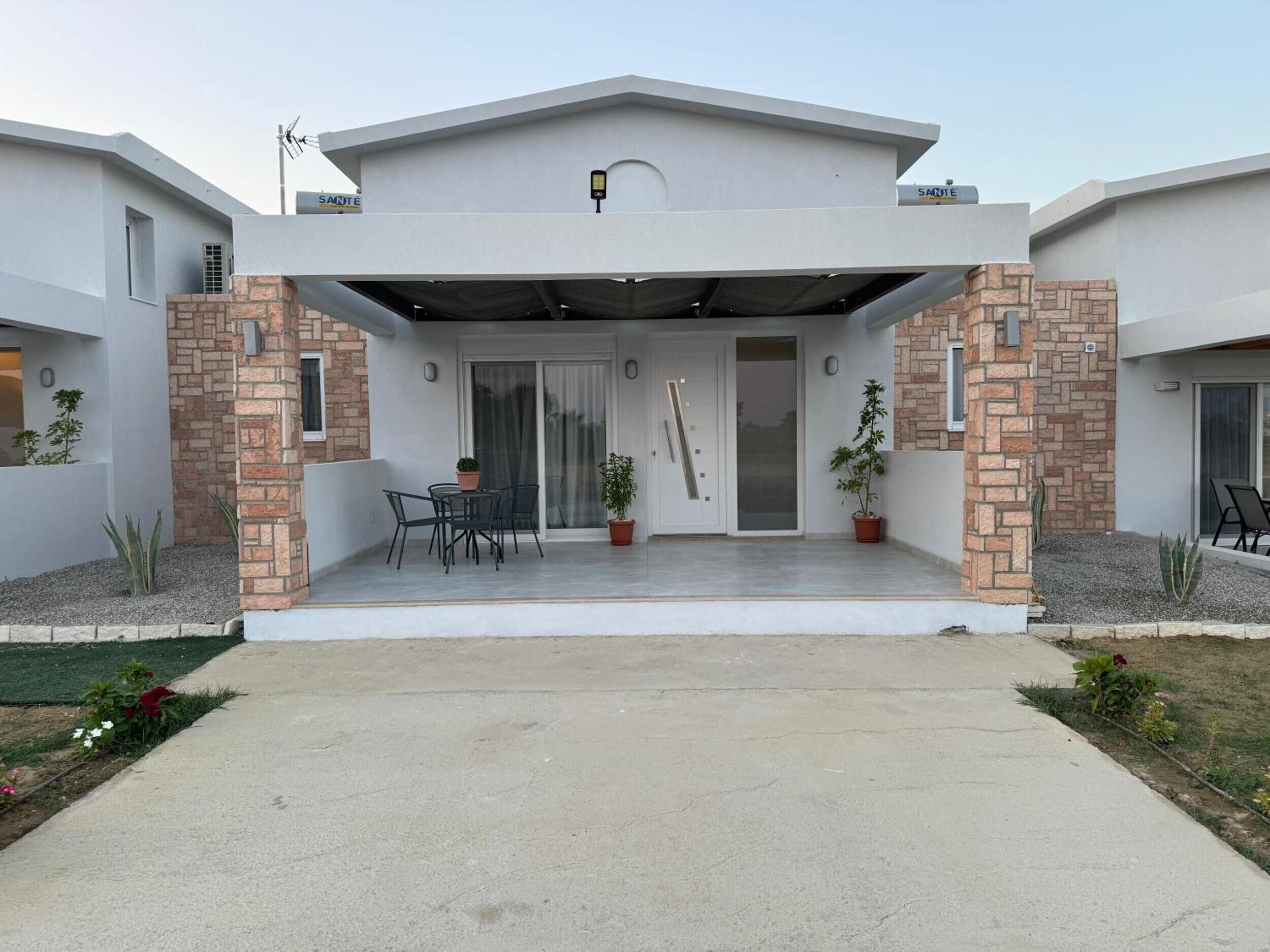 Una casa moderna a due piani con un portico coperto, un pilastro in mattoni e una porta con pannello in vetro.