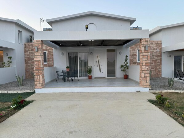 A modern two-story house with a covered patio, a brick column, and a door with a glass panel.