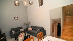 Un espace de vie compact comprenant un canapé, une table à manger pour quatre personnes et un escalier menant à un niveau supérieur.