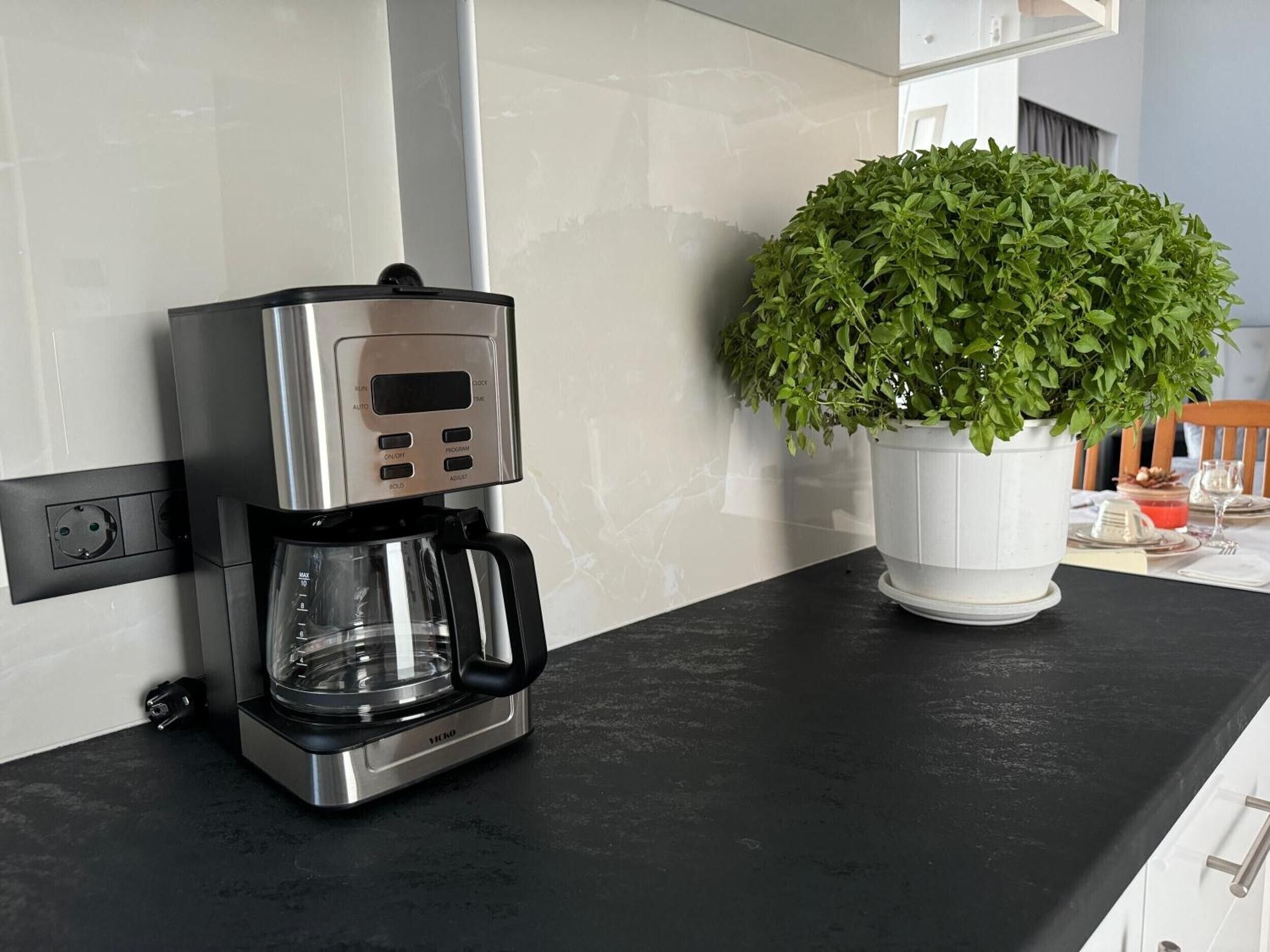 Une cuisine moderne avec une machine à café posée sur le plan de travail et une plante en pot à côté.