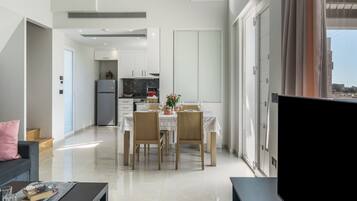A modern living room with a dining area, a kitchen, and a large window.