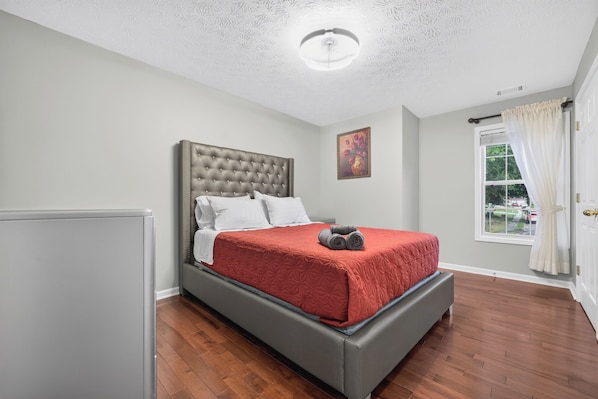 A bedroom with a bed, a window, and a door.