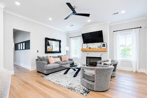 A modern living room with a grey sofa, a glass coffee table, and a fireplace. - The Chatterbox 2mi 2 Sq & Campus VelvetDitchVillas (Oxford)