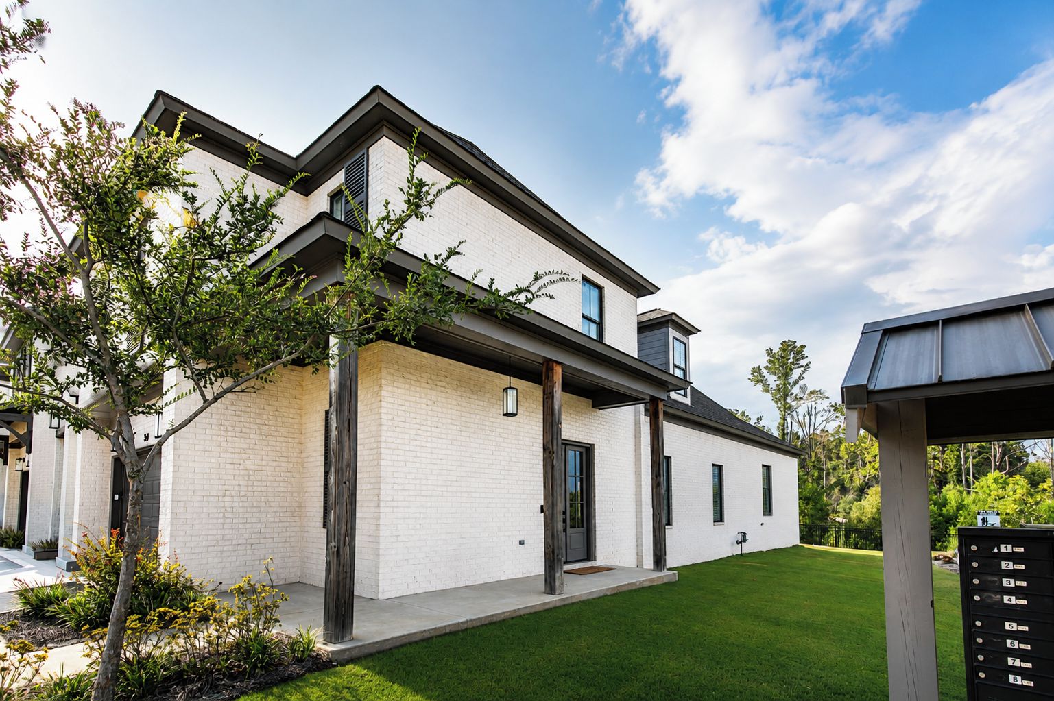 Ein modernes, zweistöckiges Haus mit Ziegelaußenwand, überdachter Veranda und gepflegtem Rasen.
