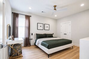 A bedroom with a bed, bedside table, curtains, a ceiling fan, and a door. - The Chatterbox 2mi 2 Sq & Campus VelvetDitchVillas (Oxford)
