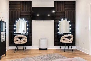 A room with two vanity mirrors with lights, a central wall-mounted TV, and a waste bin. - The Chatterbox 2mi 2 Sq & Campus VelvetDitchVillas (Oxford)