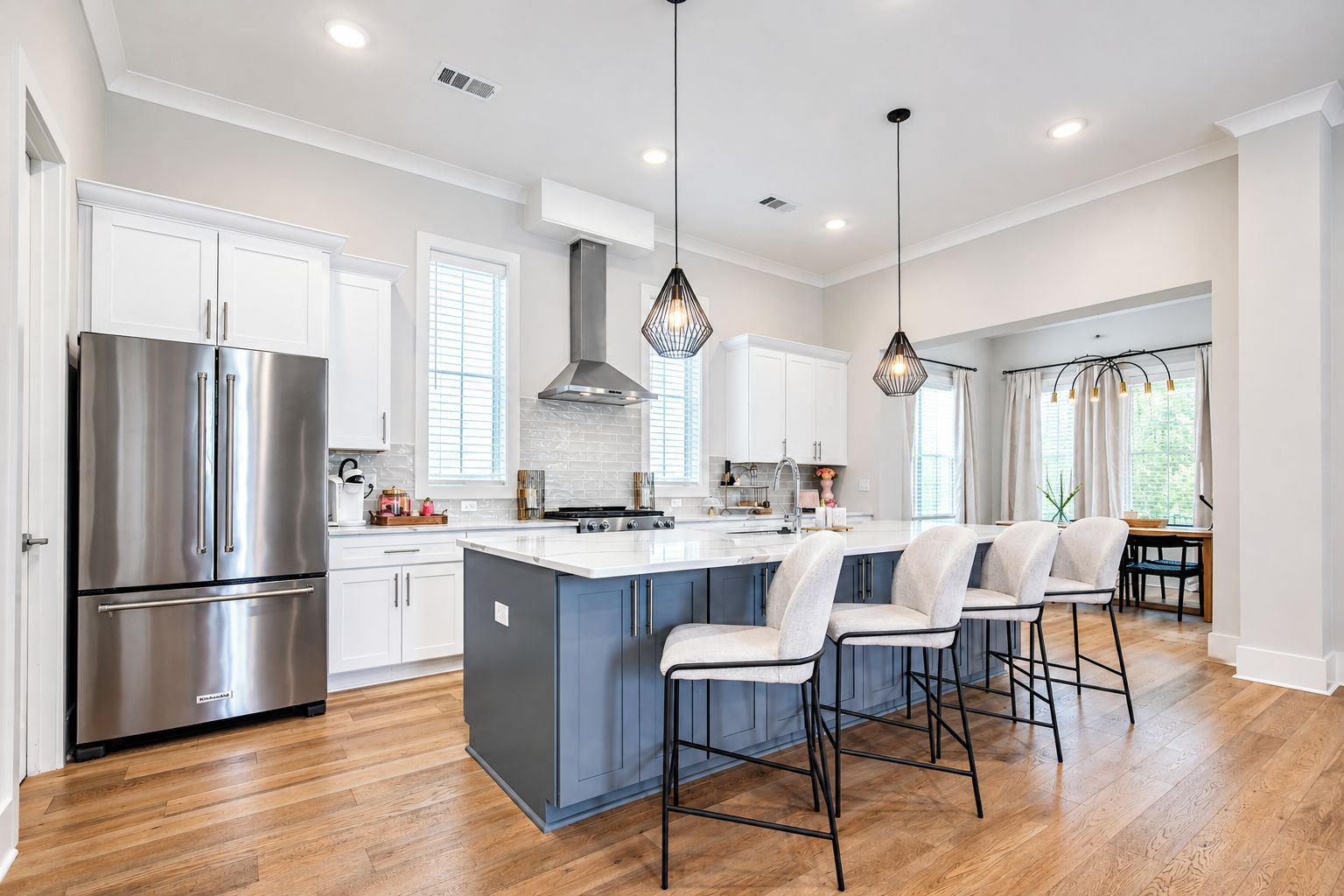 A modern kitchen with a central island, stainless steel appliances, and bar stools.