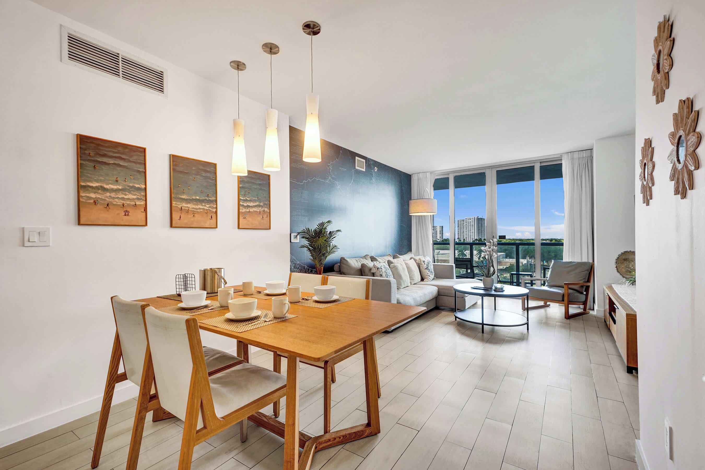 Ein modernes Wohnzimmer mit Essbereich, einer Sofagarnitur und einem großen Fenster mit Blick auf die Stadt.