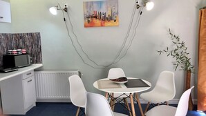 Uma sala de jantar moderna com uma mesa redonda, cadeiras brancas e um quadro na parede.