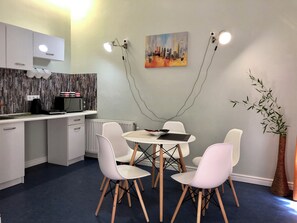 A modern kitchen with white cabinets, a microwave, and a kettle on the counter.